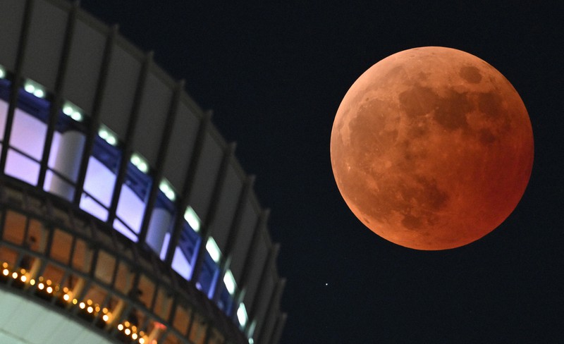 東京スカイツリーの傍らで皆既月食となった満月。月の左下にある星が、月に隠れる前の天王星＝東京都墨田区で2022年11月8日午後8時8分、手塚耕一郎撮影