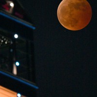 福岡タワーの近くに現れた「皆既月食」で赤銅色に染まる満月。月の左斜め下に位置する2つの星のうち、上の星が「天王星」＝福岡市早良区で2022年11月8日午後8時15分、平川義之撮影
