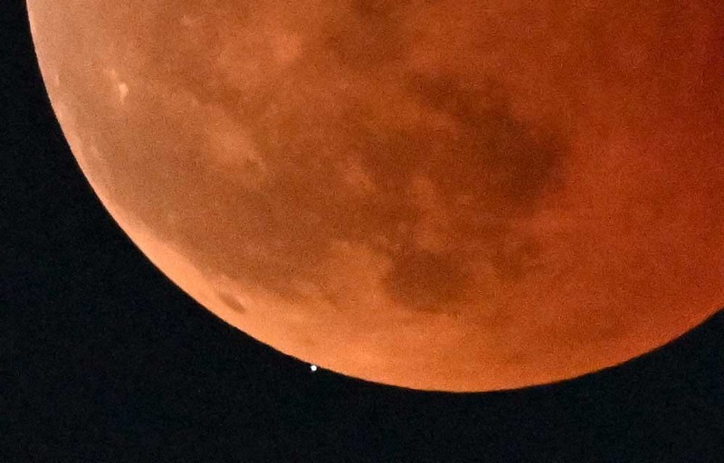 地球上から見て、天王星が月に隠されるように見える「天王星食」。「皆既月食」で赤銅色に染まる満月へと徐々に近づき隠れた＝福岡市早良区で2022年11月8日午後8時22分、平川義之撮影