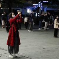 皆既月食を撮影する人たち＝東京都港区で2022年11月8日午後8時4分、猪飼健史撮影