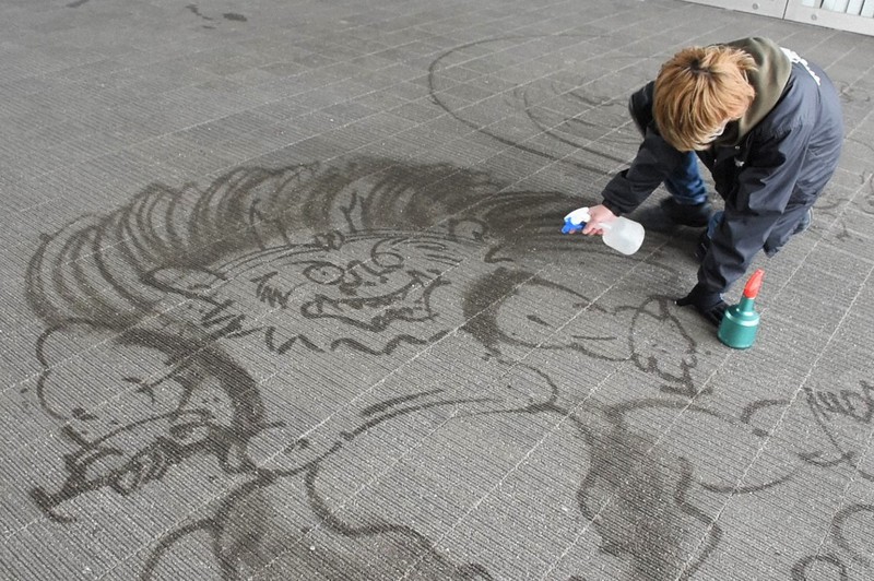 風神と雷神を水で描く堀川玄太さん=山口県宇部市のときわ公園で2022年4月18日、森紗和子撮影