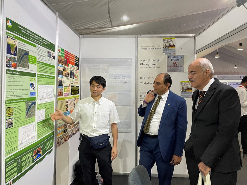 国連気候変動枠組み条約第27回締約国会議(COP27)の会場内で、参加者に研究内容を説明する北海道大大学院の平田悠さん(左)=エジプト・シャルムエルシェイクで2022年11月8日(高橋玄さん提供)