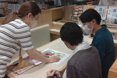 コラボメニューの試食とポップ制作の様子＝明治大学提供