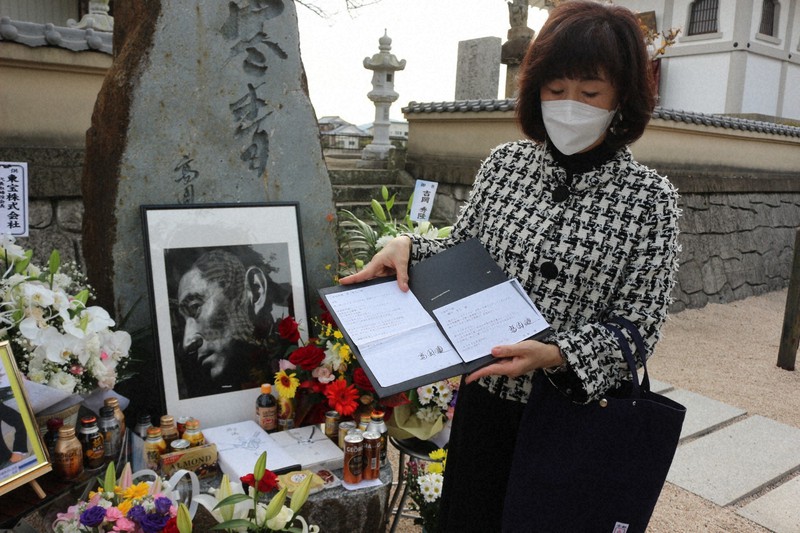 記念碑の前で、高倉さんからの手紙のコピーに目を落とす樋口さん=福岡県中間市上底井野で2022年11月10日午後4時7分、伊藤和人撮影