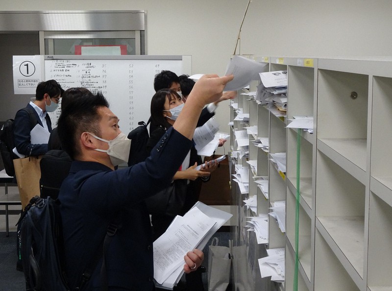 決算発表のピークが近づき、報道各社のケースに関連資料を入れる企業の担当者ら=東京都中央区の東京証券取引所で2022年11月10日午後3時38分、佐久間一輝撮影