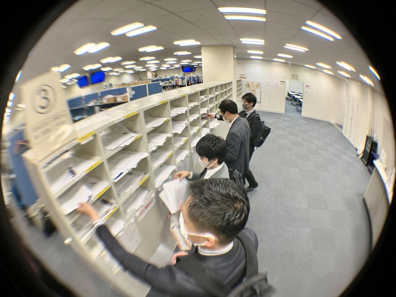 決算発表がピークを迎え、報道各社のケースに関連資料を入れる企業の担当者ら=東京都中央区の東京証券取引所で2022年11月11日午後3時34分、辻本知大撮影
