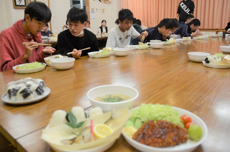 地元住民らが心を込めて準備したおにぎりや豚汁をおいしそうに食べる愛媛県立内子高校小田分校の寮生たち=同県内子町寺村で2022年11月6日午後5時44分、山中宏之撮影