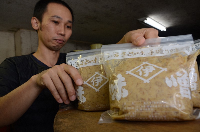 創業時から使う木だるの上に麦みその商品を並べる井伊商店3代目の井伊友博さん=愛媛県宇和島市の同店で2022年10月29日午後7時24分、鶴見泰寿撮影