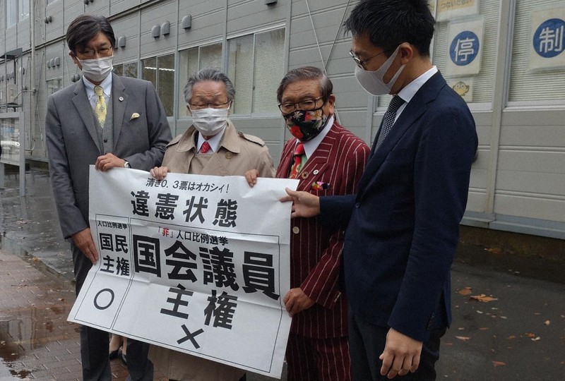 仙台高裁秋田支部の判決を受け「違憲状態」と書かれた紙を掲げる原告側の弁護士ら=秋田市で2022年11月15日、猪森万里夏撮影