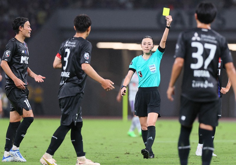 女性主審として初めてJ1のピッチに立ち、選手にイエローカードを出す山下良美さん(中央)=国立競技場で2022年9月18日、宮武祐希撮影