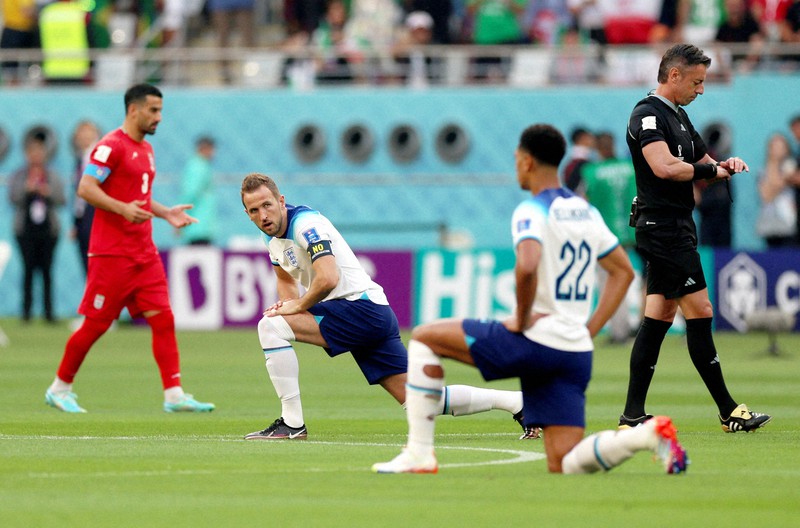 イランとの試合前に片膝をグラウンドにつけ、人種差別に対する抗議の意を示したケーン(左)らイングランドの選手たち=カタール・ドーハのハリファ国際競技場で2022年11月21日、ロイター