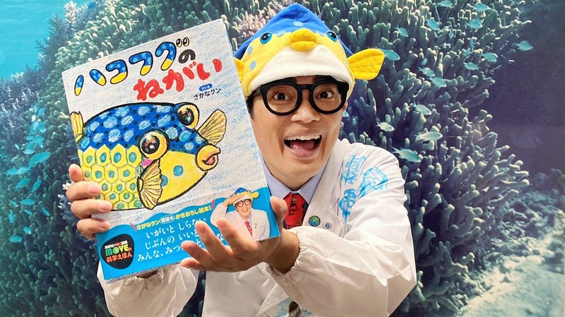 自身が描き下ろした絵本「ハコフグのねがい」を持つさかなクン=アナン・インターナショナル提供