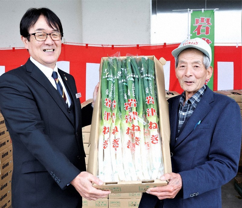 初出荷する岩津ねぎをJAたじまの山下正明代表理事専務(左)に手渡す岩津ねぎ部会の荒川欣也部会長=兵庫県朝来市和田山町のJAたじま和田山営農生活センターで2022年11月22日午前11時53分、幸長由子撮影