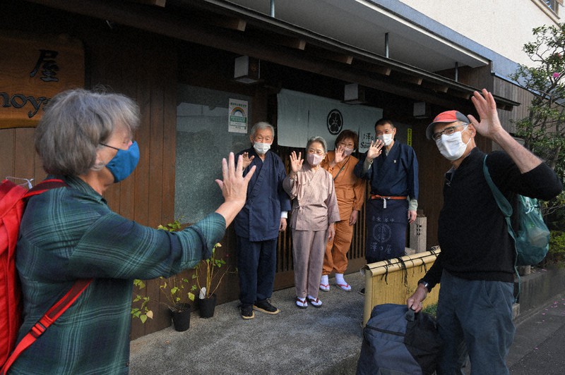 16年ぶりに宿泊した米国の夫婦を見送る「澤の屋」店主の澤功さん(奥左端)たち=東京都台東区で2022年11月19日、宮間俊樹撮影