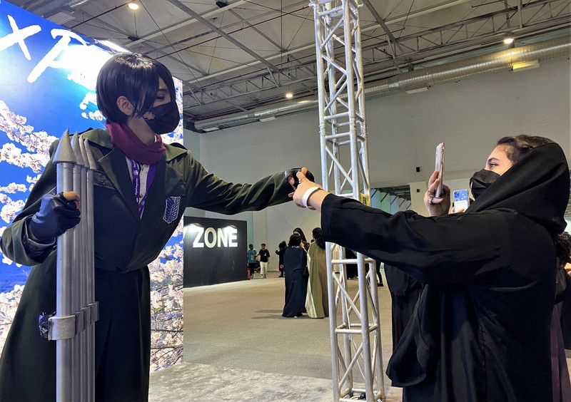 「サウジアニメエキスポ」の会場で、女性コスプレーヤー(左)の写真を撮る全身黒衣の少女=リヤドで2022年10月27日午後7時18分、真野森作撮影