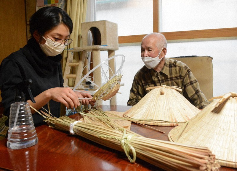 佐藤春一さん(右)のアドバイスを聞きながら、スゲ笠を編む水沢結衣さん=新潟県魚沼市穴沢で、板鼻幸雄撮影
