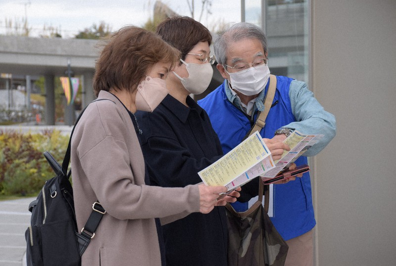 来園者に無料で楽しめる場所を案内する堀木幹夫さん(右)=愛知県長久手市の愛・地球博記念公園で2022年11月30日午前11時19分、酒井志帆撮影