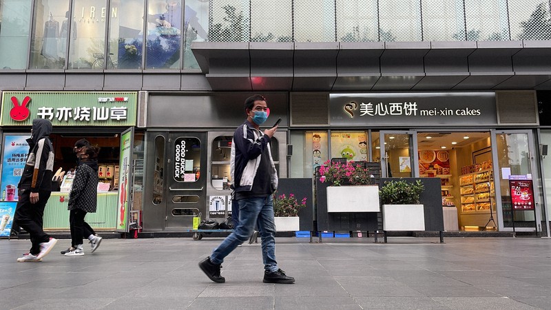 規制が緩和され、再開した店のそばを通り過ぎる市民=広東省広州市で2022年12月1日、AP