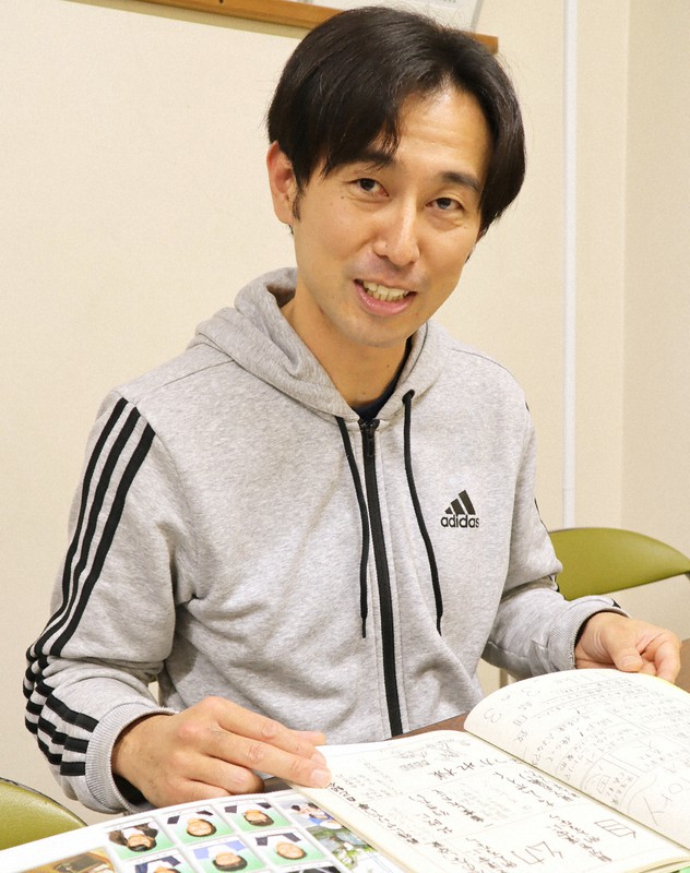 冨安健洋選手が三筑中3年生だった時のクラス文集やアルバムを見て当時を振り返る谷口新さん=福岡市南区筑紫丘の市立野間中で2022年11月30日午後5時42分、谷由美子撮影