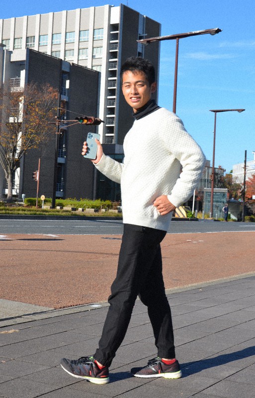 スマホを手に競歩のポーズをする名古屋大陸上部の鈴木智大さん=名古屋市千種区で2022年11月25日、川瀬慎一朗撮影