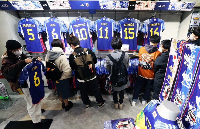 サッカー日本代表のユニホームを選ぶ買い物客ら=東京都渋谷区で2022年12月5日午後6時8分、小出洋平撮影