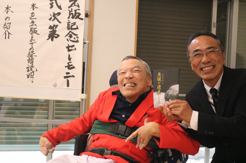 「恵規の遺産」を著し笑顔を見せる成清さんと「福祉ネット宝箱」の覚知事務局長(右)=柳川市三橋町蒲船津の第1宝箱そらまめで2022年11月30日正午ごろ、降旗英峰撮影