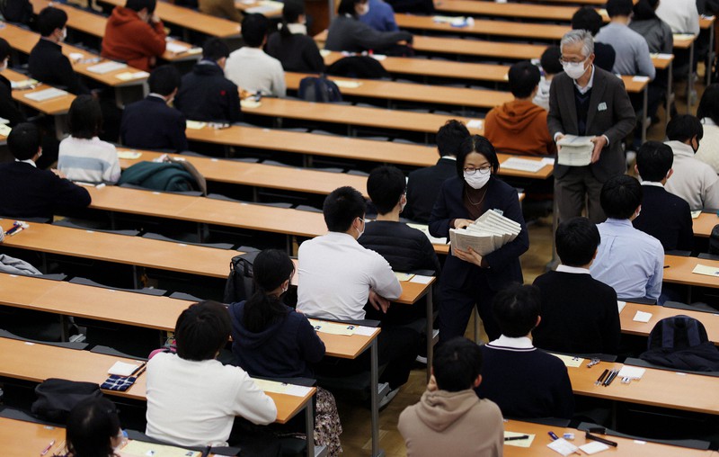 2022年1月15日に行われた大学入学共通テスト初日。会場となった東大の試験室内で問題用紙を配付する試験官たち=東京都文京区で、吉田航太撮影