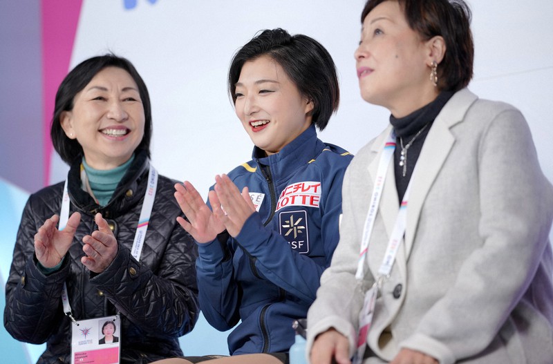 女子SPでシーズンベストの得点を見て、キスアンドクライで拍手する坂本花織(中央)=イタリア・トリノのパラベラ競技場で2022年12月9日、貝塚太一撮影