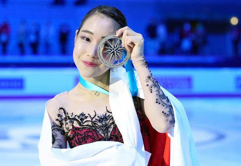 女子フリーで逆転初優勝し、笑顔でメダルを掲げる三原舞依＝イタリア・トリノのパラベラ競技場で2022年12月10日、貝塚太一撮影