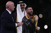 Argentina's Lionel Messi holds up the trophy flanked by FIFA President Gianni Infantino and The Emir of Qatar Sheikh Tamim bin Hamad Al Thani after winning the World Cup final soccer match between Argentina and France at the Lusail Stadium in Lusail, Qatar, on Dec.18, 2022. (AP Photo/Manu Fernandez)