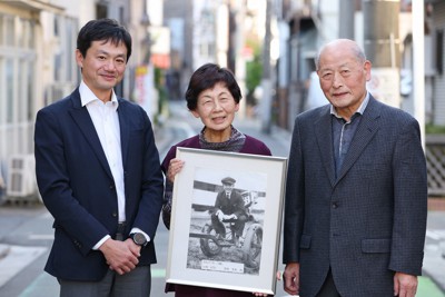 羽太文夫さんの写真を手にする長女の服部正子さん（中央）、その夫の守さん（右）、吉田重雄さんの孫の中村素康さん。戦火に散ったパイロットと生き抜いたパイロット、その2人の家族が顔を合わせて思いを語り合った＝東京都荒川区で2022年11月9日、猪飼健史撮影