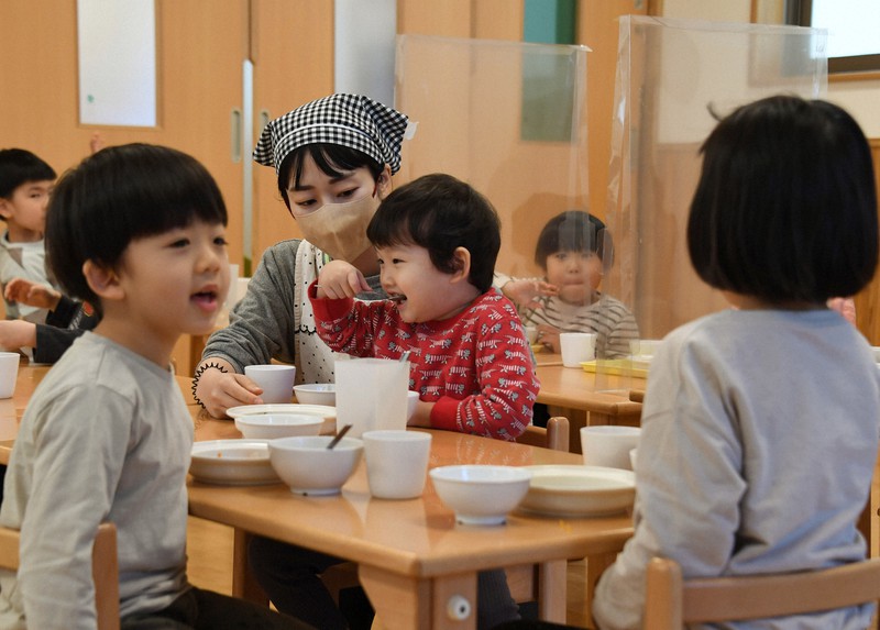 コロナ禍の中、間隔を空け、対面しないようにして子どもに食事をさせる保育士=東京都世田谷区で2022年12月8日午前11時56分、宮本明登撮影