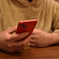 男性は自身が逮捕されたニュース映像を見つめ、自分を戒める＝2023年2月10日午後6時10分、木原真希撮影