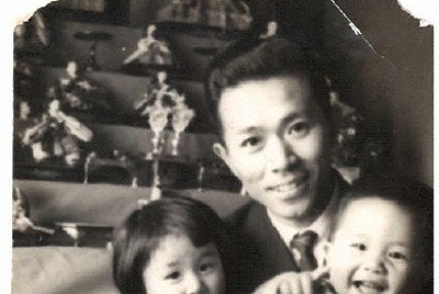 1963年3月、ひな人形の前で2歳上の姉（左）と私（右）を抱いた父。この4年後に胃がんで亡くなった＝当時住んでいた金沢市で撮影