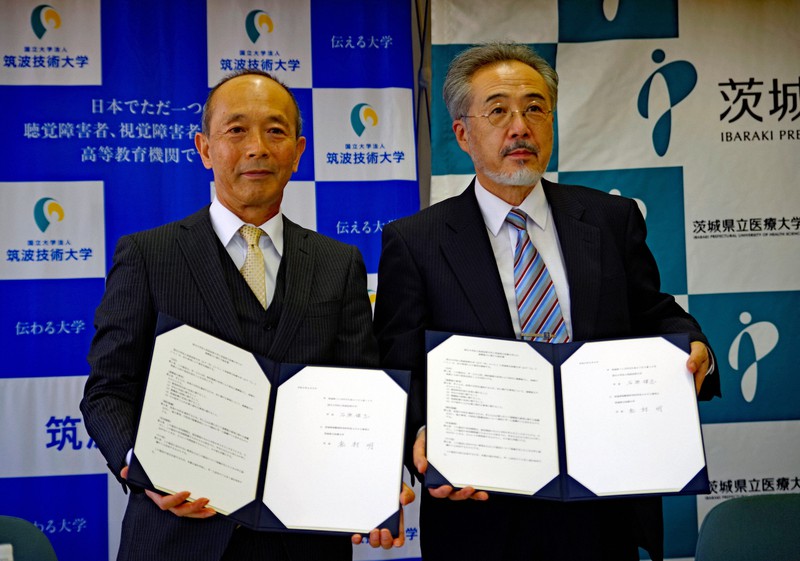 署名した協定書を持つ石原学長（左）と松村学長（右）