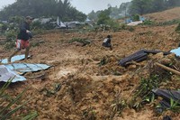 In this frame grab made from video released by Indonesia's National Disaster Management Agency (BNPB), people inpspect the site where a landslide hit a village on Serasan Island, Natuna regency, Indonesia, on March 6, 2023. (BNPB via AP)