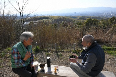 伏見桃山城や大阪市街を展望できる大岩山展望所で野だてをする長谷川秀明さん（左）。右は大岩山ふもとに住む加藤有治さん＝京都市伏見区で