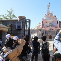 2020年9月にオープンした大型アトラクション「美女と野獣“魔法のものがたり”」の前で写真を撮る来場客＝千葉県浦安市で2020年9月28日午前8時36分、玉城達郎撮影