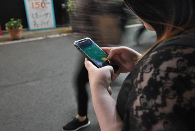 路上に立ちながらスマートフォンを見るユズ。この頃も歌舞伎町を離れるかどうかで迷っていた＝東京都内で2022年6月、春増翔太撮影