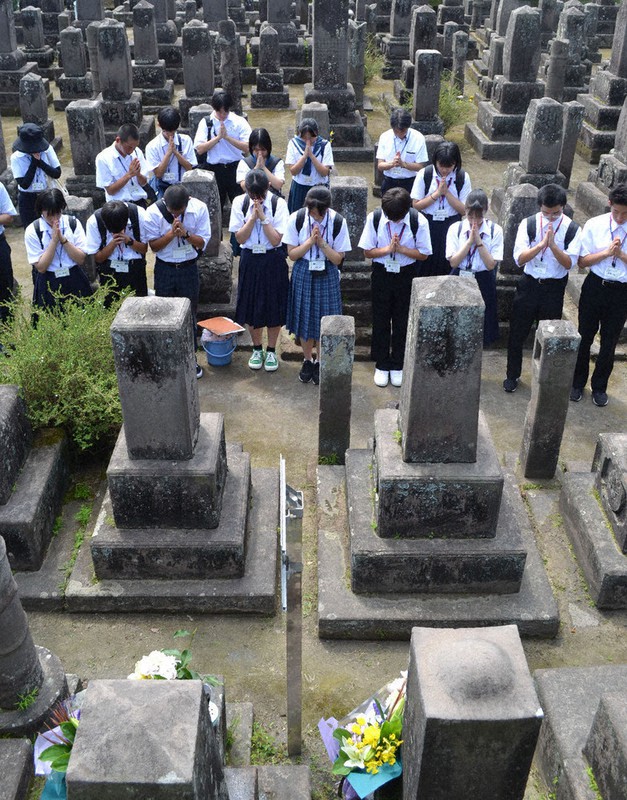 献花した庄内藩士の墓(手前)に手を合わせる中学生ら