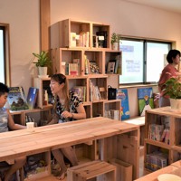 キッチンも備えた図書スペースの1階。正方形の木枠の「一箱本棚」には、寄付協力者が子どもたちに読んでほしいオススメの本や漫画を置いており、自由に読むことができる＝兵庫県西宮市六湛寺町で2023年8月1日午後0時7分、稲田佳代撮影