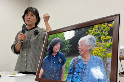 対馬丸事件の生存者で、7月に急逝した平良啓子さんと一緒に写った写真を立てて講話する次女の次子さん＝那覇市の対馬丸記念館で2023年8月12日午後3時18分、比嘉洋撮影