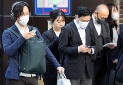 スマートフォンを手に信号を待つ人たち＝東京都千代田区で2023年3月22日午前8時34分、幾島健太郎撮影
