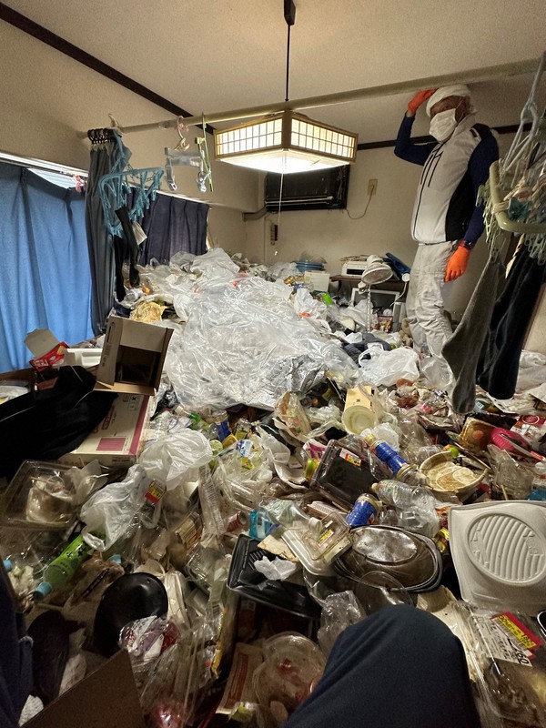 ごみが積み重なった部屋を清掃する新家喜夫社長＝神戸市で2023年8月、テンシュカク提供