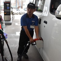ガソリン価格が高騰するなか、客の車に給油をするガソリンスタンドの店員＝福岡市中央区で2023年8月31日午前11時56分、山口響撮影