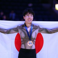 男子3位となり表彰式で日の丸を背に笑顔を見せる佐藤駿＝米アレンで2023年10月21日、猪飼健史撮影