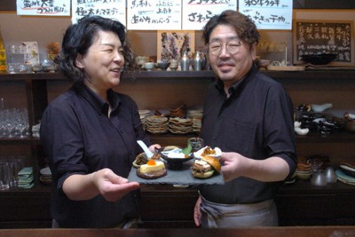 自慢の「はち寅8品」を手にする矢口勝則さん（右）、恵さん夫婦＝兵庫県宝塚市川面5で、稲垣淳撮影