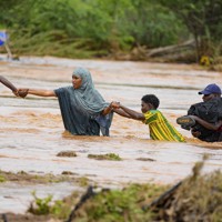 大雨に見舞われ、冠水した道路を歩く住民。東アフリカでは広範囲で大雨が続き、被害が拡大している＝ケニア南東部で2023年11月25日、AP