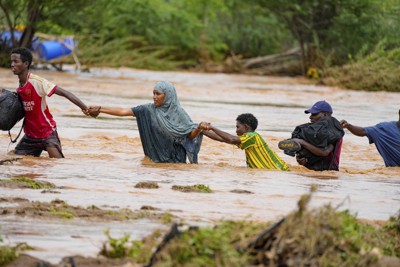 大雨に見舞われ、冠水した道路を歩く住民。東アフリカでは広範囲で大雨が続き、被害が拡大している＝ケニア南東部で2023年11月25日、AP