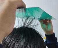A primary school student makes their hair stand on end with static electricity generated by rubbing a plastic sheet on their head, on Nov. 18, 2023, in Tokyo. (Mainichi/Haruna Okuyama)